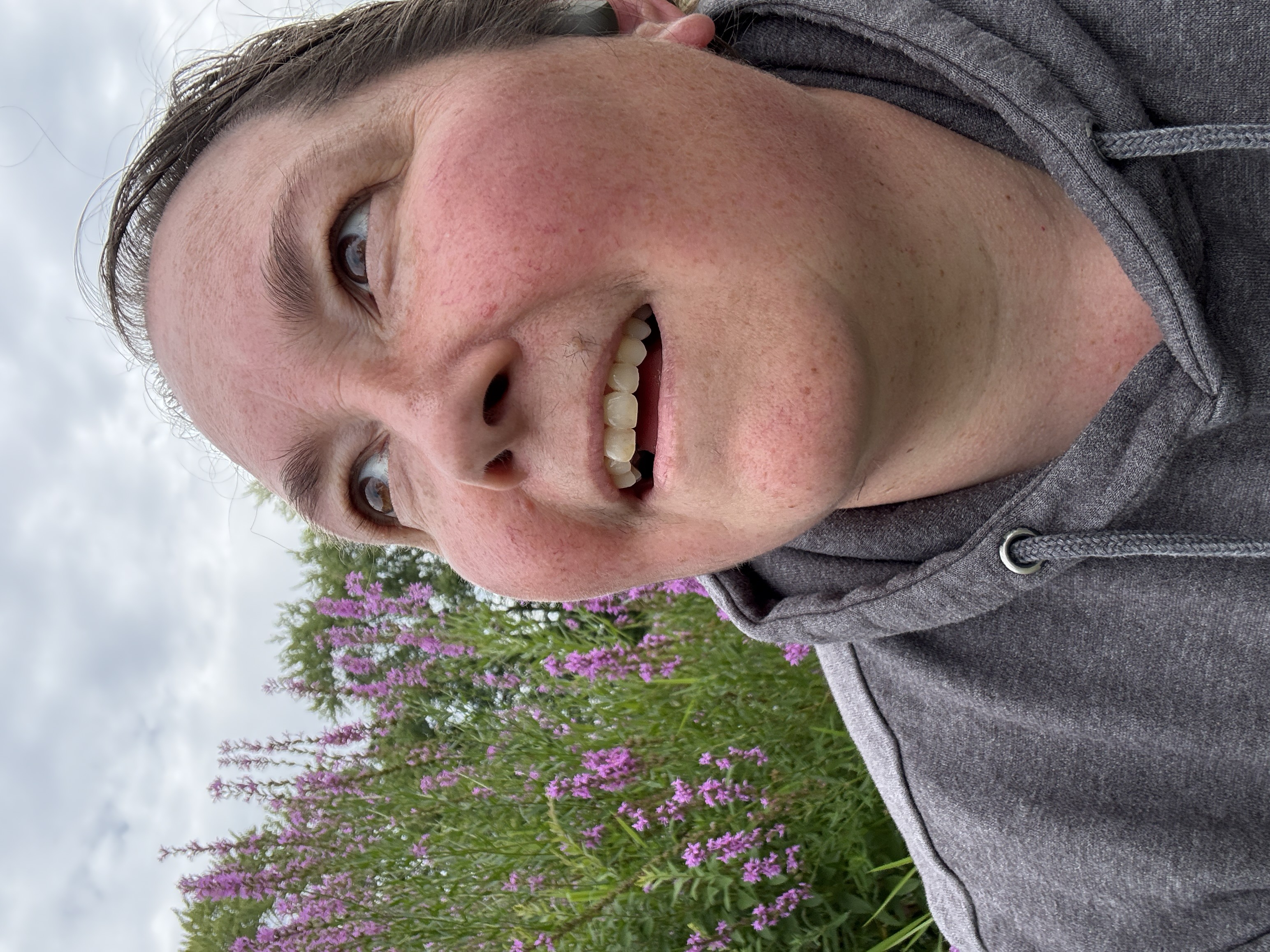 Photo of Esther Rhatigan looking up in front of purple flowers